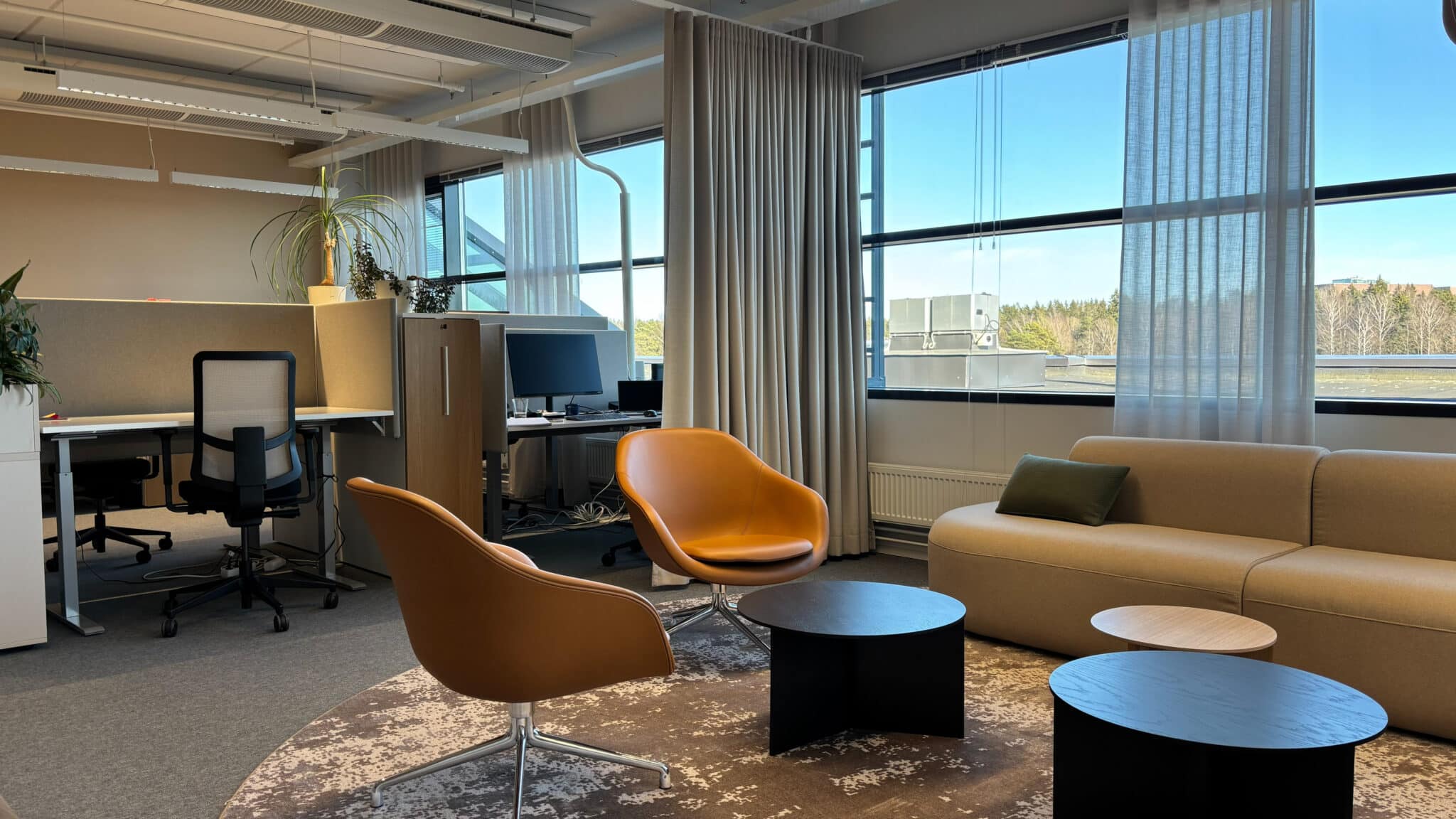 Maanläheisten värein sisustettu nykyaikainen toimitila Mansku 105:ssä. Lounge aluella keltaiset nojatuolit ja beige sohva.