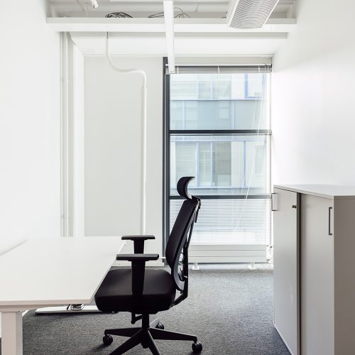 Yhden hengen työhuone toimistohotellissa. Huoneessa on pöytä, työtuoli ja kaappi.