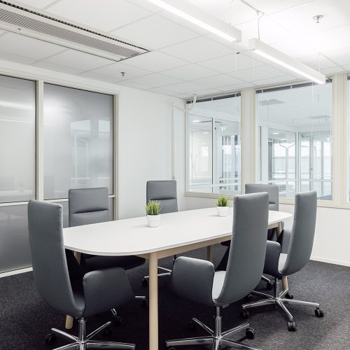 Toimistorakennuksen neuvottelutilassa on valkoinen pöytä ja kuusi tuolia sen ympärillä.