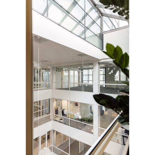 Mannerheimintie 105, toimistorakennuksen aula on keskeltä korkea ja siinä on lasiseinät eri kerroksiin.